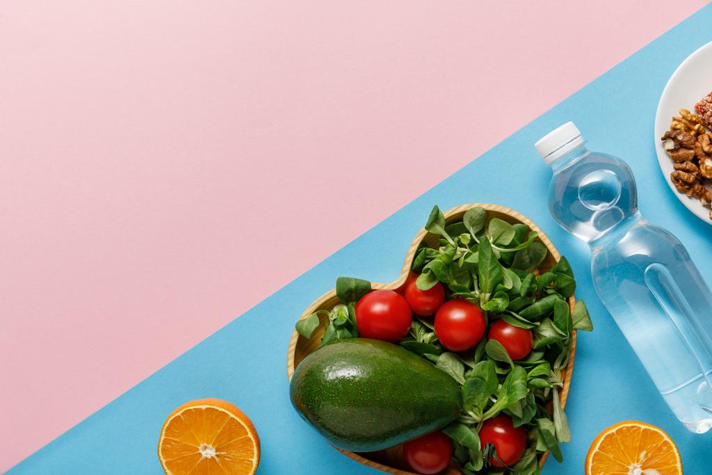 płaskie lay z sałatką warzywną, pomarańcze, wody i orzechy na różowym i niebieskim tle - Zdjęcie, obraz
