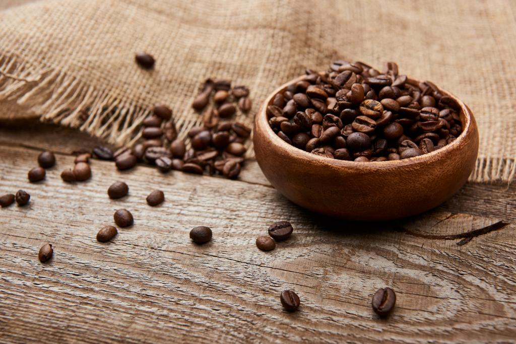 свіжі смажені кавові зерна в мисці біля мішковини на дерев'яній дошці
 - Фото, зображення