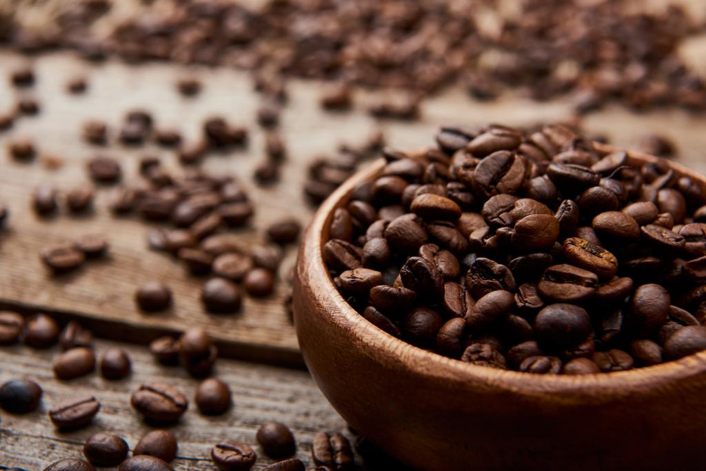 Nahaufnahme gerösteter Kaffeebohnen in Schale auf Holzbrett - Foto, Bild