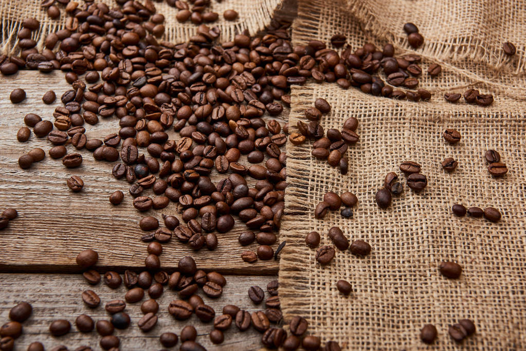 coffee beans near sackcloth on wooden background - Photo, Image