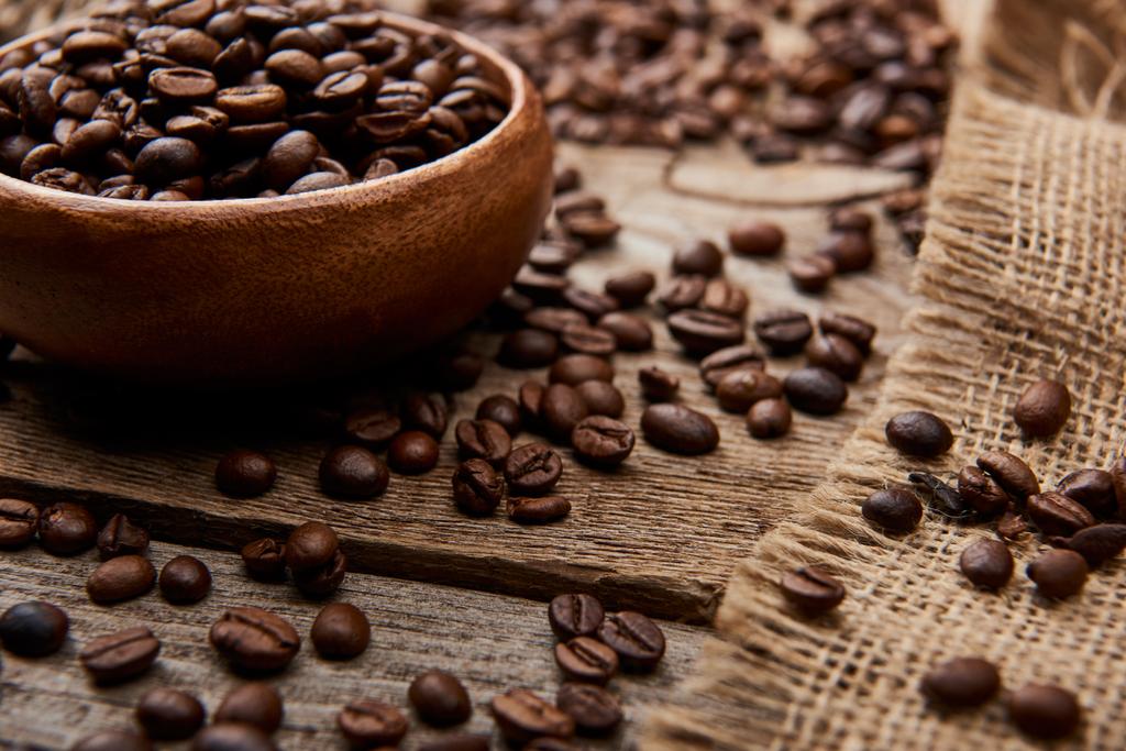 close up view of coffee beans on bowl on wooden background - Photo, Image