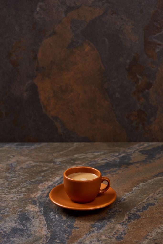 lahodná káva v hnědém šálku na talířku na mramorovém stole - Fotografie, Obrázek