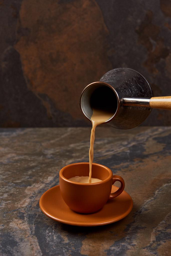 наливая горячий кофе из цезава в чашку на мраморной поверхности
 - Фото, изображение
