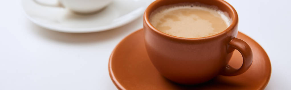panoramatický záběr lahodné kávy v hnědém šálku na bílém povrchu - Fotografie, Obrázek