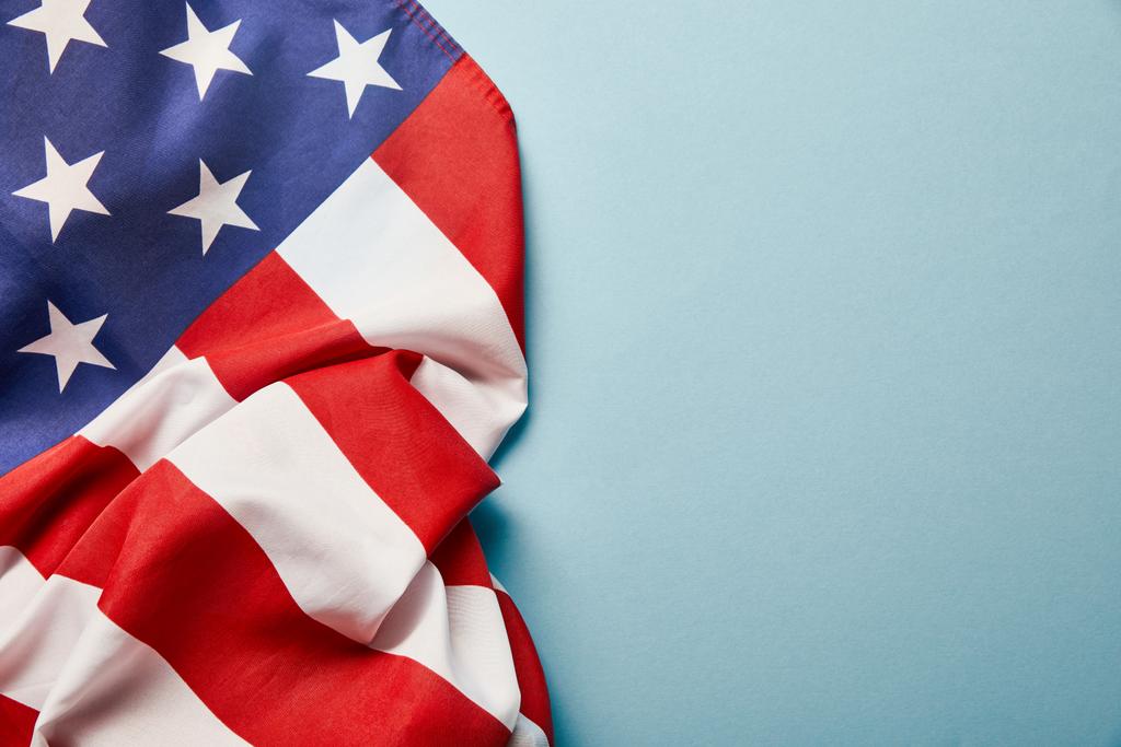 Draufsicht auf zerknitterte amerikanische Flagge auf blauem Hintergrund mit Kopierraum - Foto, Bild