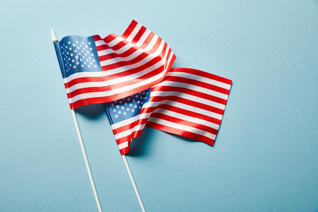 κορυφαία άποψη των αμερικανικών σημαίες σε ραβδιά σε μπλε φόντο - Φωτογραφία, εικόνα