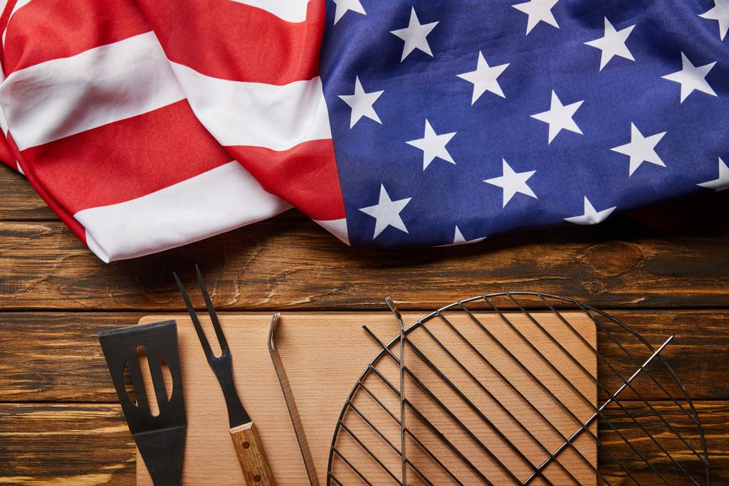 vista dall'alto della bandiera americana accartocciata e attrezzatura per barbecue su tavolo rustico in legno
 - Foto, immagini