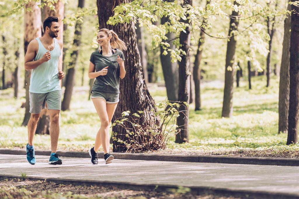 jóképű férfi és vonzó nő beszél, miközben fut a parkban - Fotó, kép