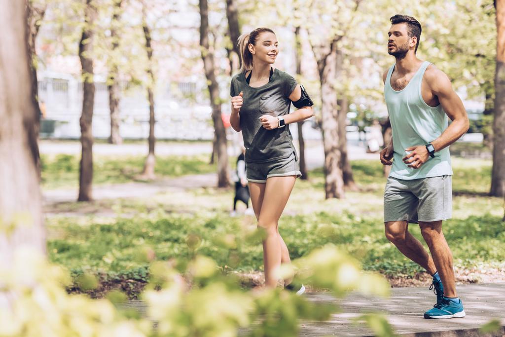 公園でジョギング笑顔の女性とハンサムな男の選択的な焦点 - 写真・画像