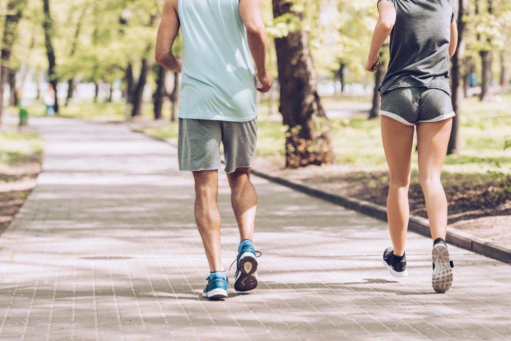 обрізаний знімок чоловіка в жінці біжить разом вздовж прогулянки в парку
 - Фото, зображення