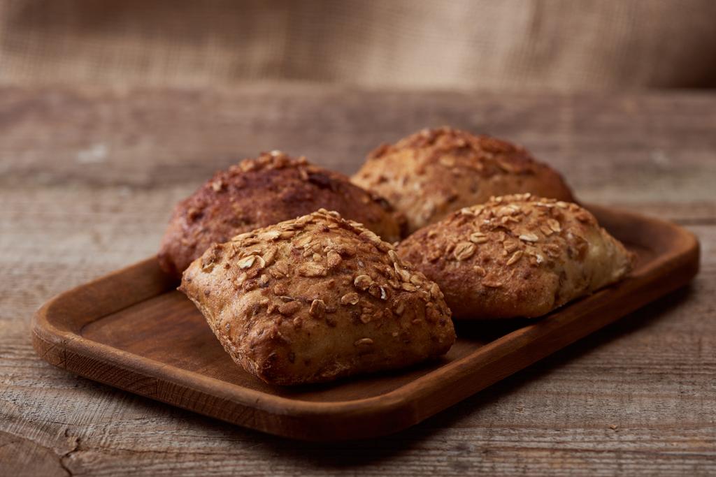 vers gebakken broodjes met granen op houten plank op tafel - Foto, afbeelding