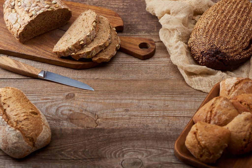 corte recién horneado y pan entero y bollos en mesa de madera
 - Foto, Imagen