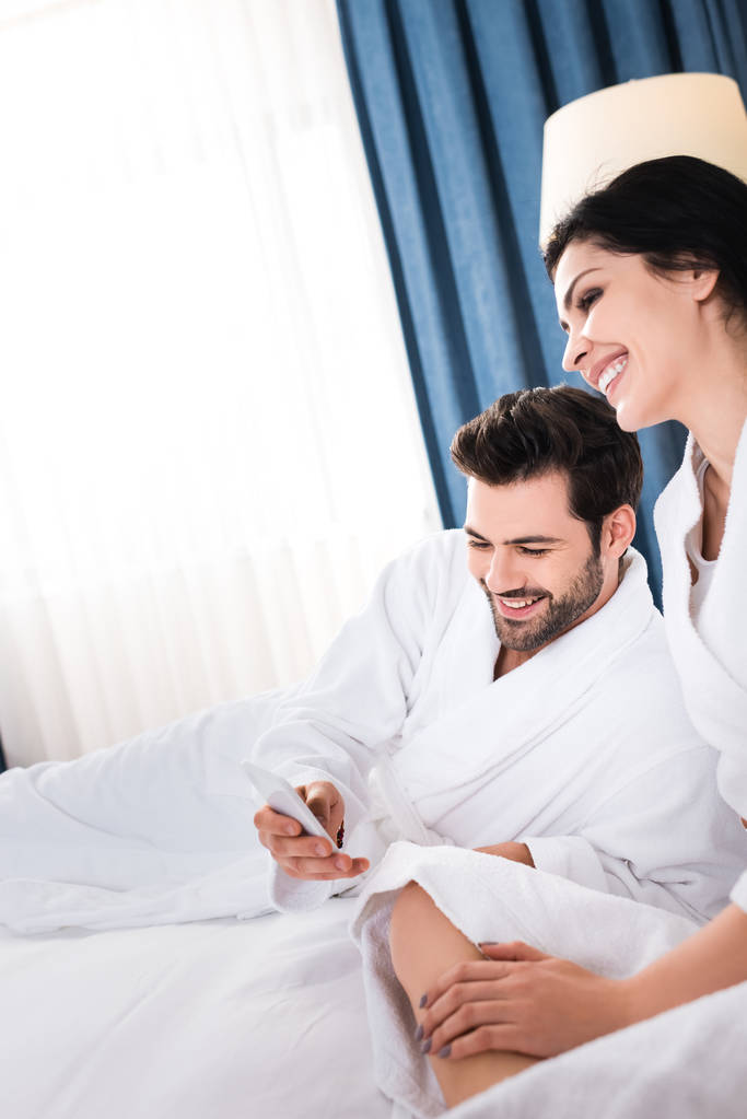 cheerful bearded man using smartphone near happy brunette woman  - Photo, Image