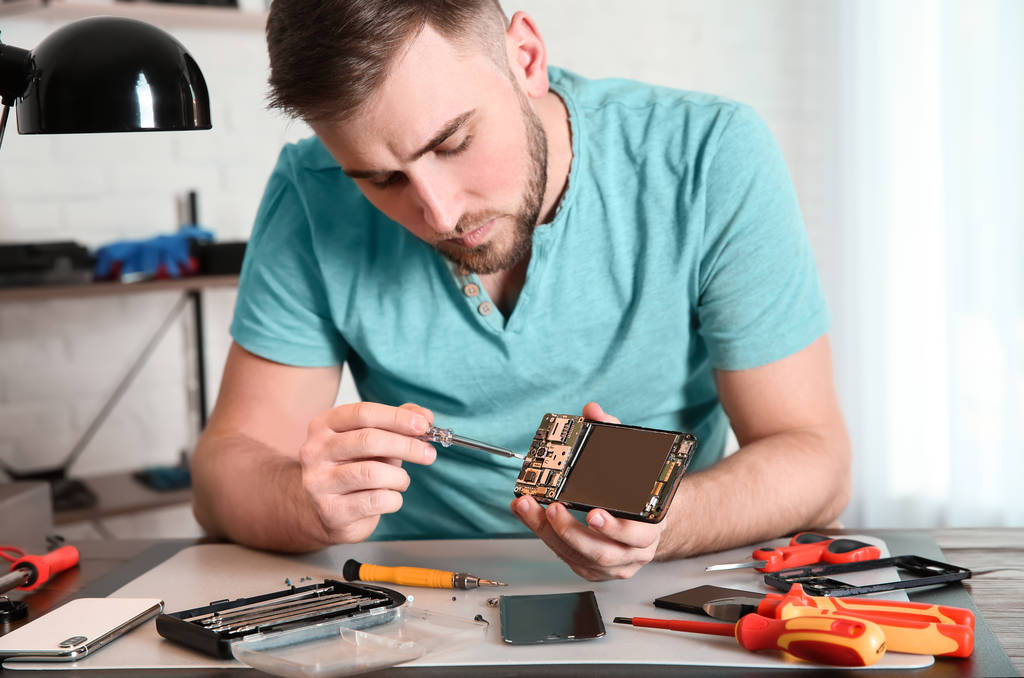 Techniker repariert Handy am Tisch in Werkstatt - Foto, Bild