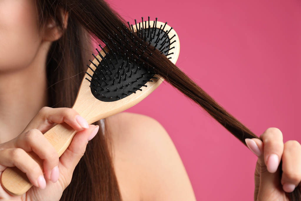 Woman with hair brush on color background, closeup - Photo, Image