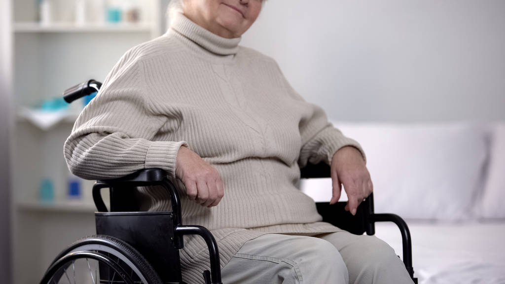 Behinderte ältere Frau sitzt im Rollstuhl im Pflegeheim, Sozialversicherung - Foto, Bild