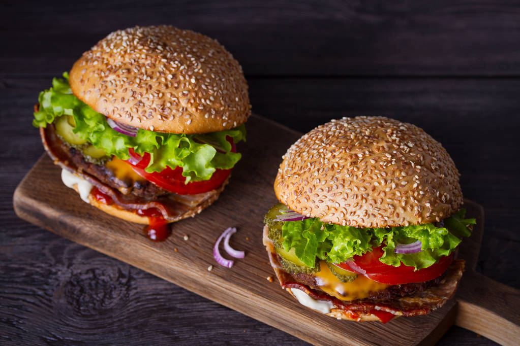 Delicious homemade beef burgers with bacon on wooden chopping board. horizontal - Photo, Image