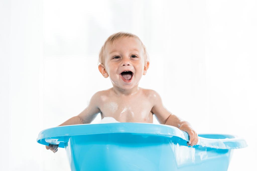 青い赤ちゃんのバスタブでお風呂を取っている間に笑顔愛らしい幼児の子供  - 写真・画像