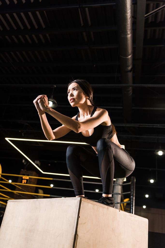 Niedrigwinkel-Ansicht attraktiver Frau bei Kniebeuge-Übungen auf Kniebeuge-Box  - Foto, Bild