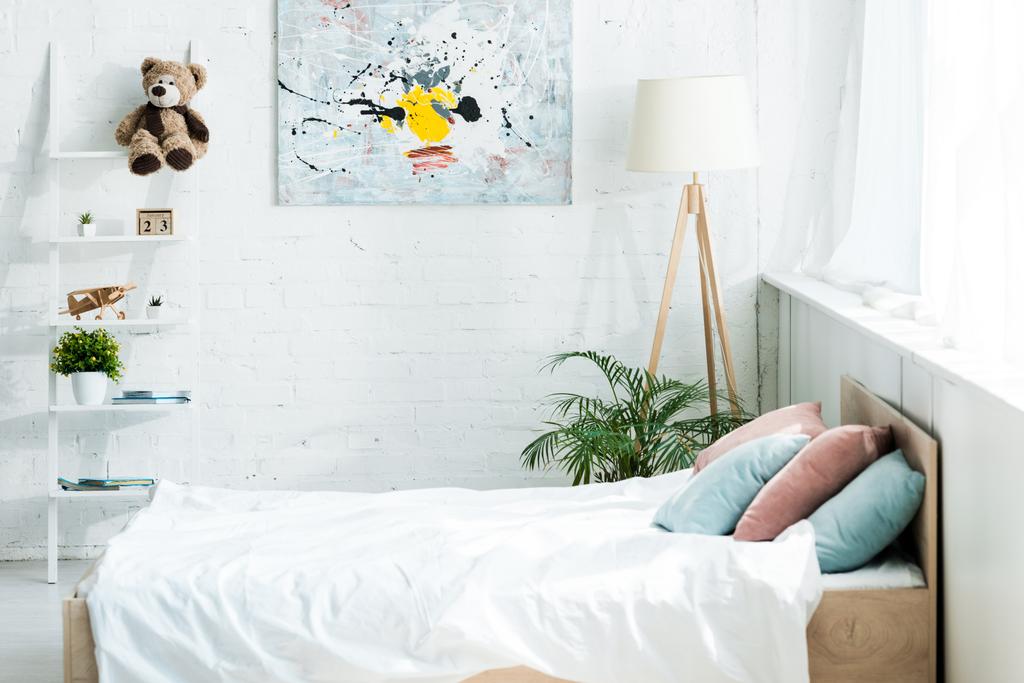 łóżko z białą pościelą, niebieskie i różowe poduszki w pobliżu szafy i malarstwa  - Zdjęcie, obraz