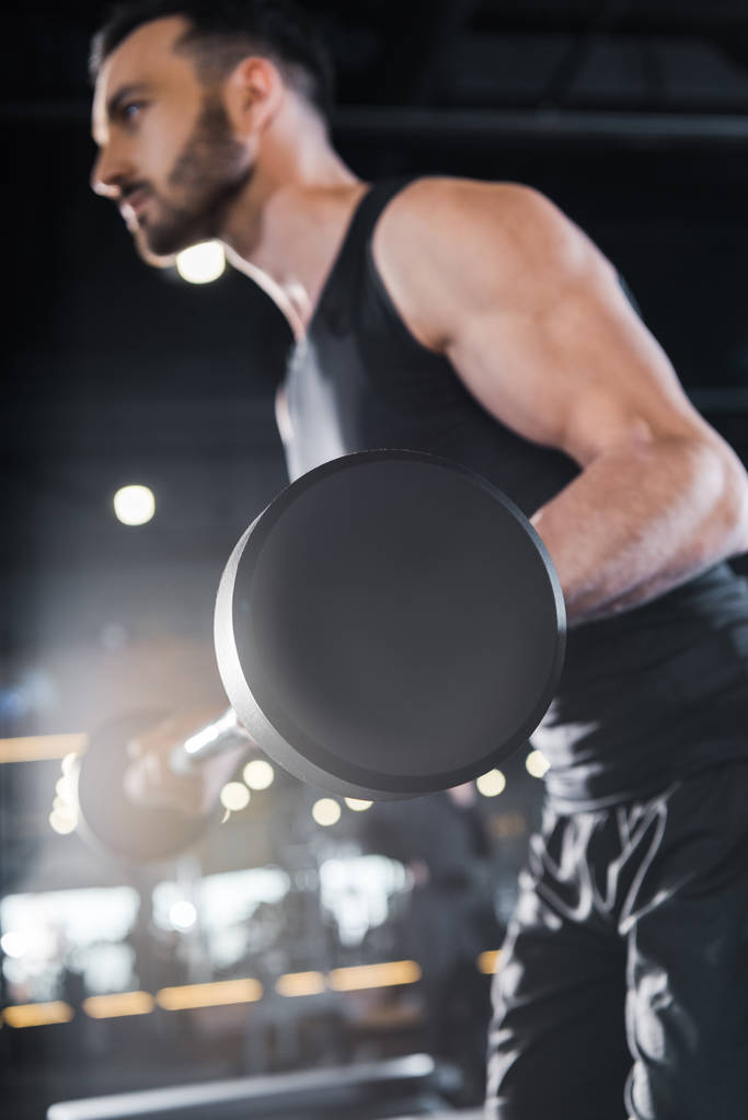 selectieve focus van knappe sterke man trainen met zware barbell in de sportschool  - Foto, afbeelding