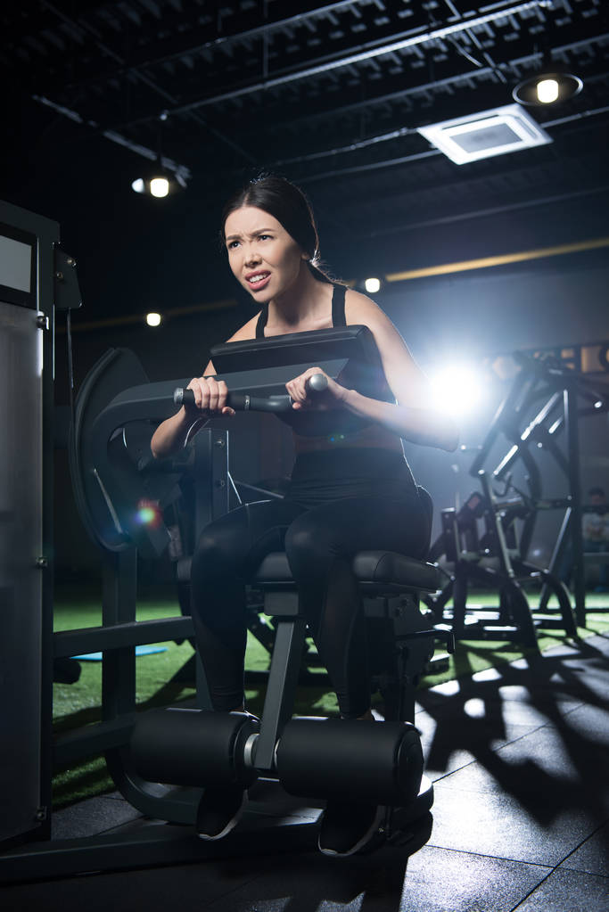 Tiefansicht müder Sportlerin beim Training an Trainingsgeräten im Fitnessstudio  - Foto, Bild