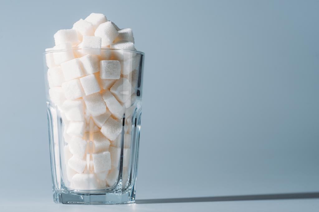 білі кубики цукру в склянці на сірому фоні з копією простору
 - Фото, зображення