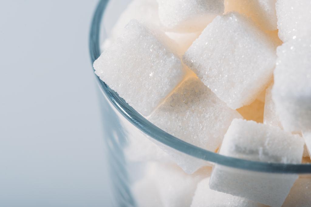 close up view of white sugar cubes in glass on grey background - Photo, Image