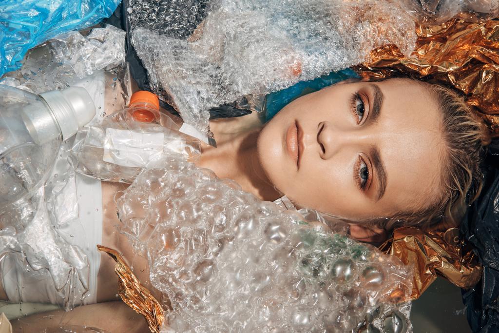 a fiatal nőről a műanyaghulladék-fürdőkádban, a környezetszennyezés koncepciójában felülnézet - Fotó, kép