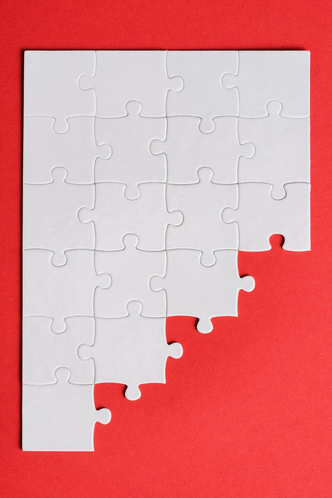 bovenaanzicht van wit verbonden puzzelstukken geïsoleerd op rood  - Foto, afbeelding