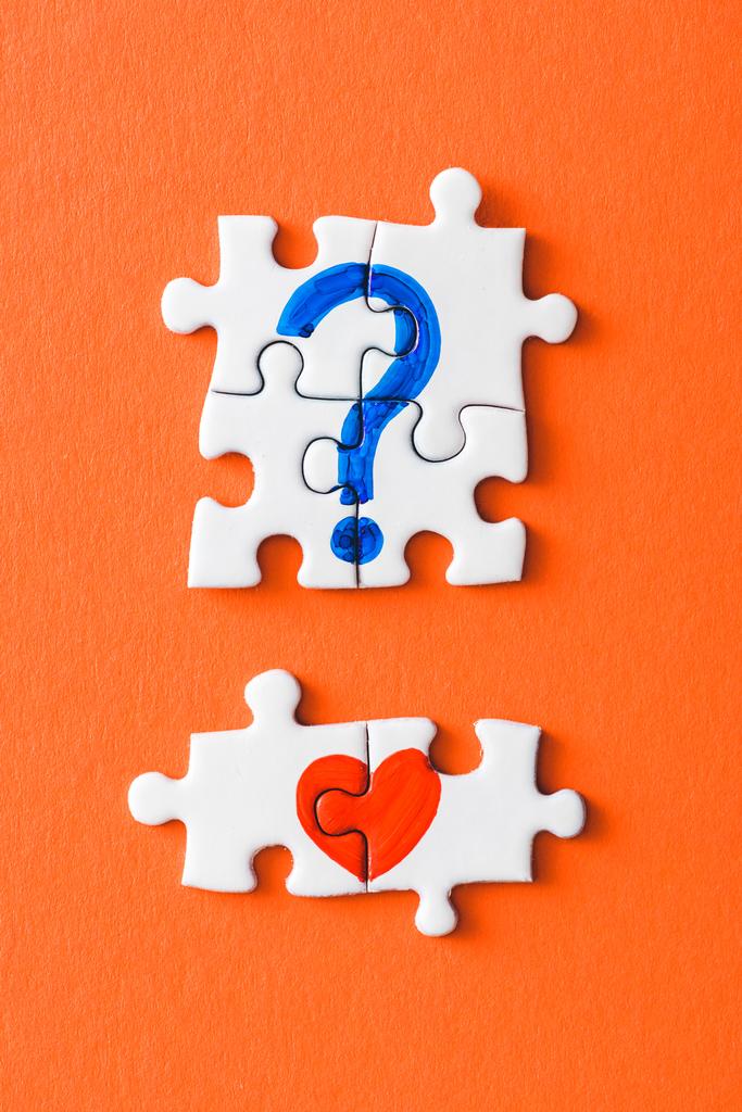 a kapcsolódó puzzle-darabok felülnézete húzott vörös szívvel és kék kérdőjellel a narancs - Fotó, kép