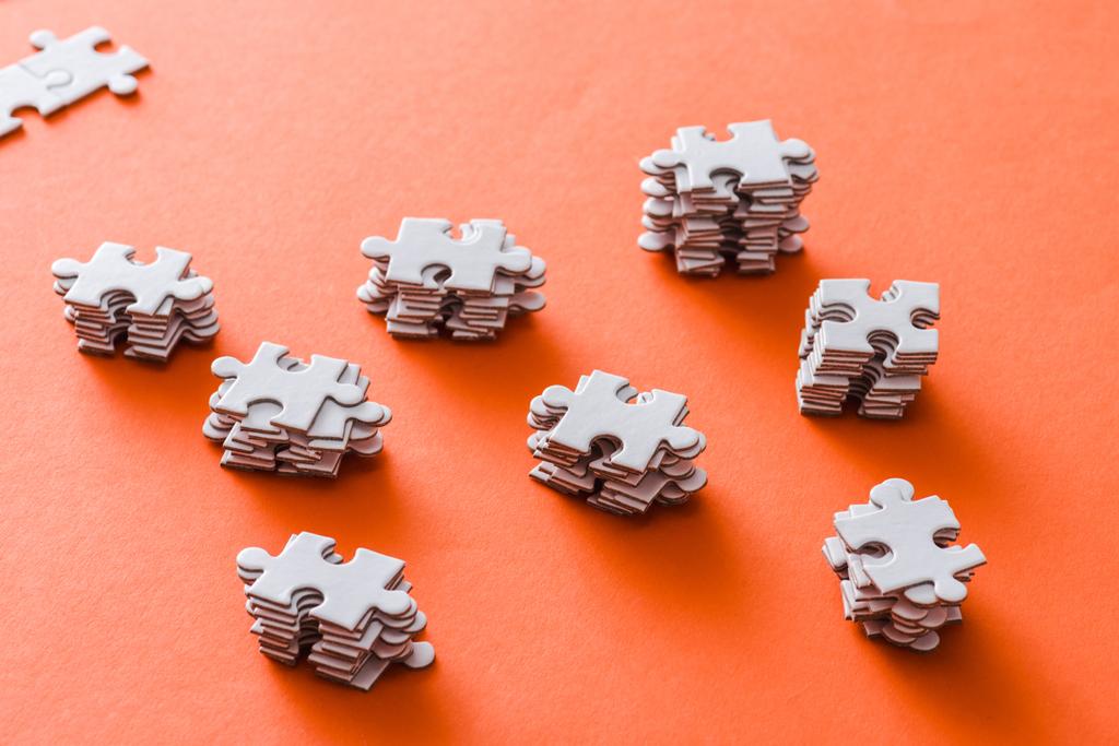 селективный фокус сложенных белых кусочков головоломки на оранжевом
 - Фото, изображение