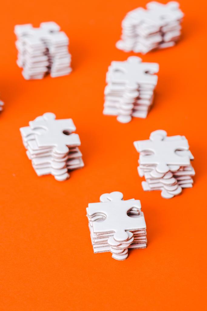 selektive Fokussierung von Stapeln mit weißen Puzzleteilen auf orange - Foto, Bild