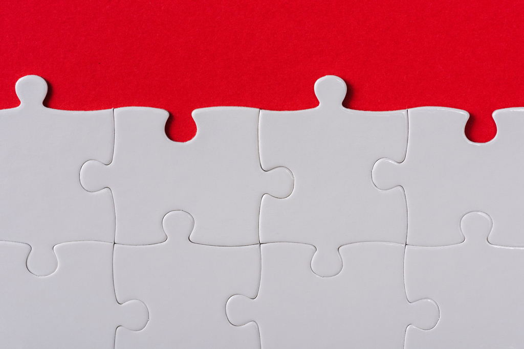 Ansicht von oben nach passenden weißen Puzzleteilen isoliert auf rot  - Foto, Bild