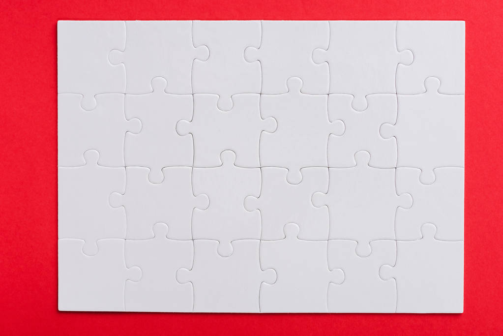 top view of connected white puzzle pieces with copy space isolated on red  - Photo, Image