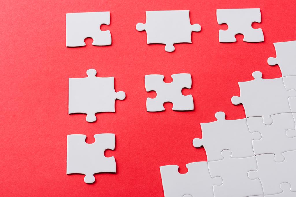 white connected and separate jigsaw puzzle pieces isolated on red  - Photo, Image