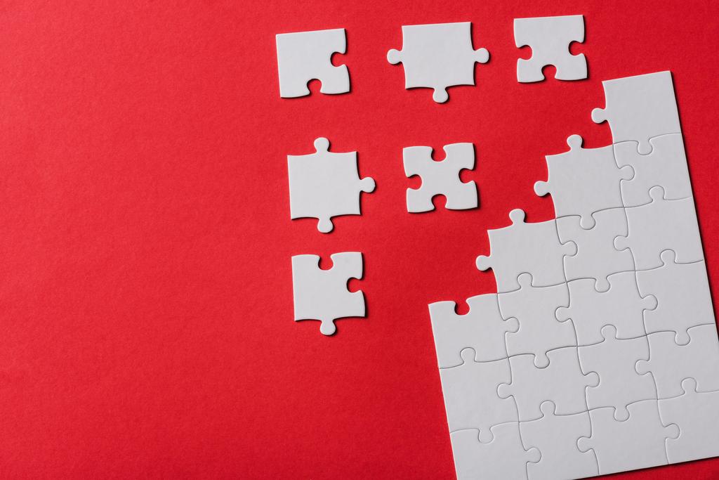 top view of connected and separate jigsaw puzzle pieces isolated on red  - Photo, Image