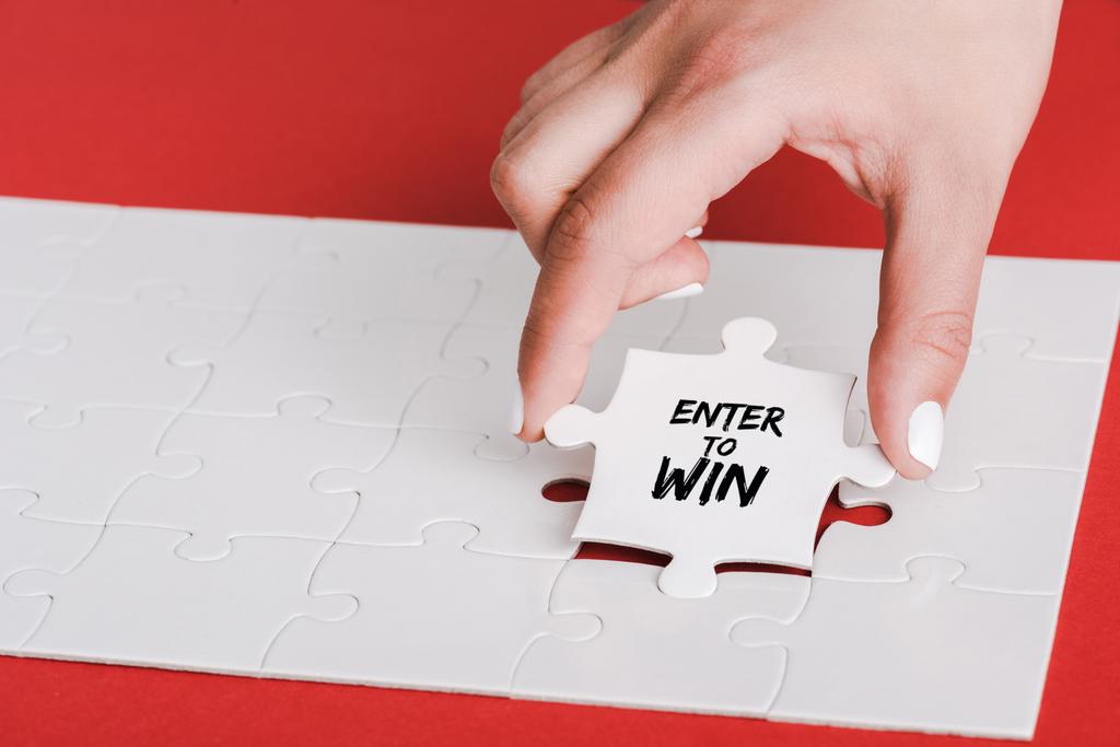 cropped of woman holding jigsaw with enter to win lettering near connected white puzzle pieces on red - Photo, Image