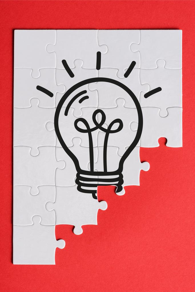 top view of white connected puzzle pieces with light bulb isolated on red  - Photo, Image