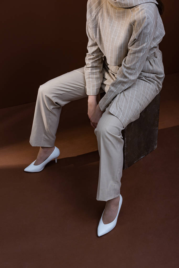 vista ad alto angolo della donna alla moda in elegante usura seduta su sfondo marrone
 - Foto, immagini