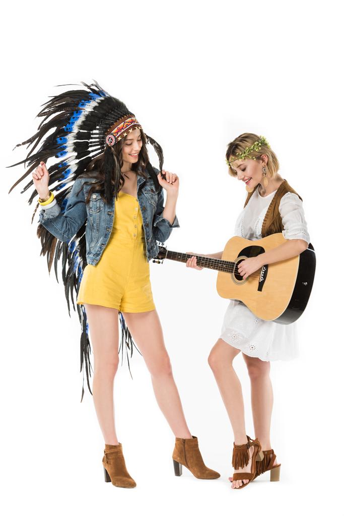 pełny widok długości dwóch biseksualistów hippie dziewcząt w indyjskim nakryciu głowy i wieniec z gitary akustycznej na białym tle - Zdjęcie, obraz