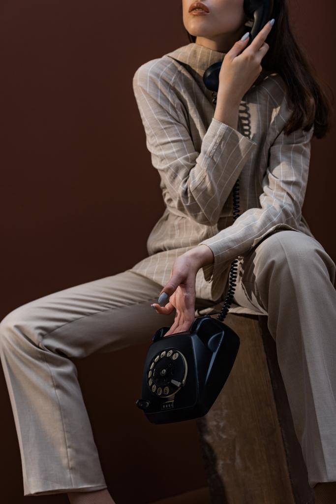Ausgeschnittene Ansicht eines erwachsenen Modells mit Hörer in der Hand, der auf einem Kasten sitzt - Foto, Bild