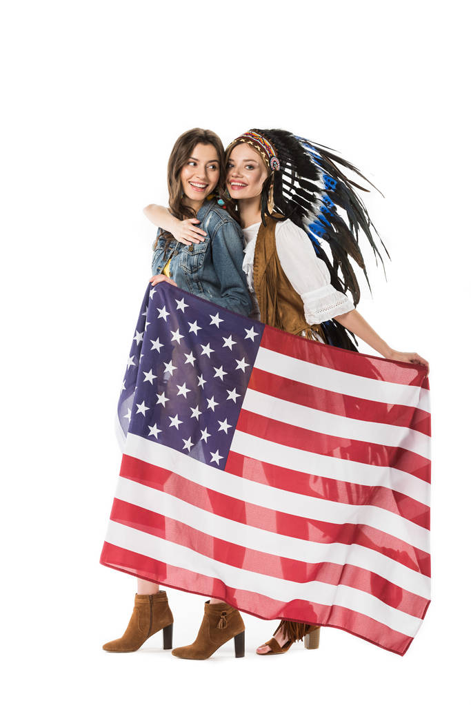 πλήρους μήκους θέα δύο αμφιφυλόφιλων χίππις που κατέχουν αμερικάνικη σημαία και αγκαλιάζονται απομονωμένα σε λευκό - Φωτογραφία, εικόνα
