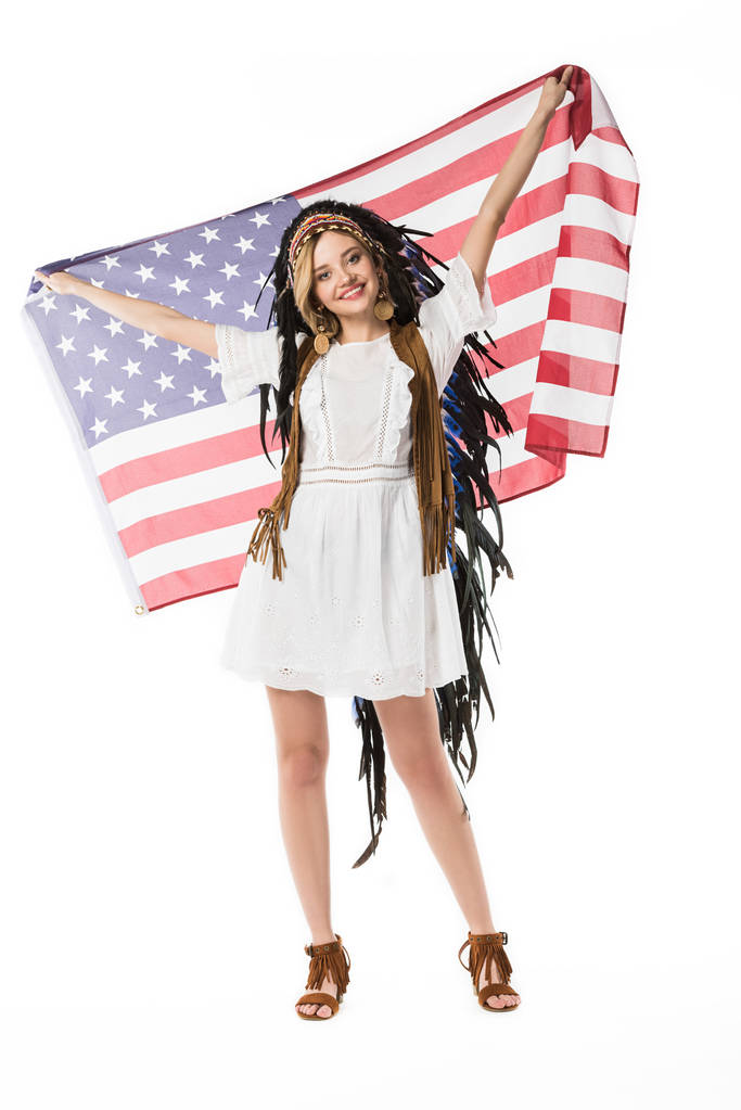 full length view of happy hippie girl in indian headdress holding american flag isolated on white - Photo, Image