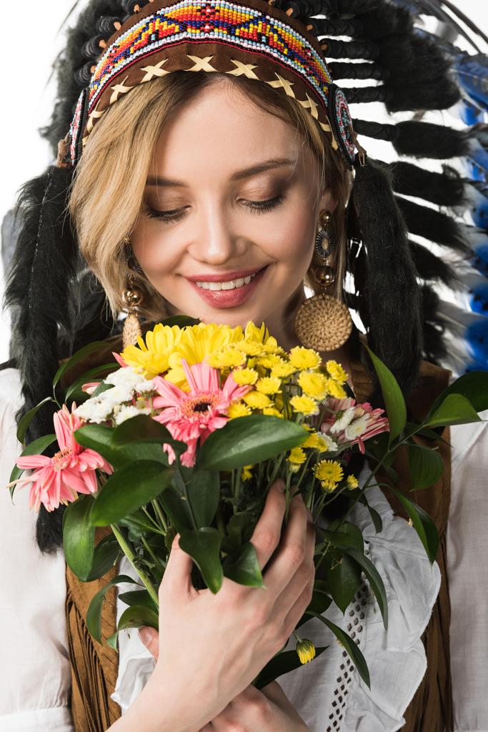 okouzlující dívka v indiánské helmě, která drží květiny izolovaná na bílém - Fotografie, Obrázek