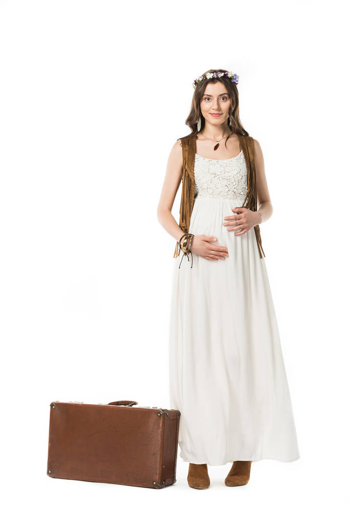 πλήρες μήκος θέα της χαμογελαστή έγκυο γυναίκα σε στεφάνι με βαλίτσα απομονωμένη σε λευκό - Φωτογραφία, εικόνα