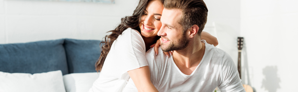 朝ベッドで男を抱きしめる幸せな笑顔の女性のパノラマショット - 写真・画像