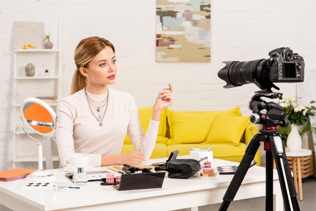 Blogger, která sedí u stolu s dekorativní kosmetikou před videokamerou - Fotografie, Obrázek