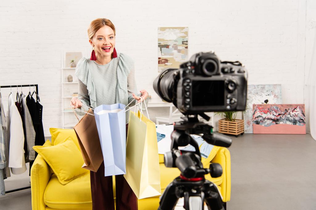 gülümseyen blogger evde video kamera önünde alışveriş çantaları tutarak - Fotoğraf, Görsel