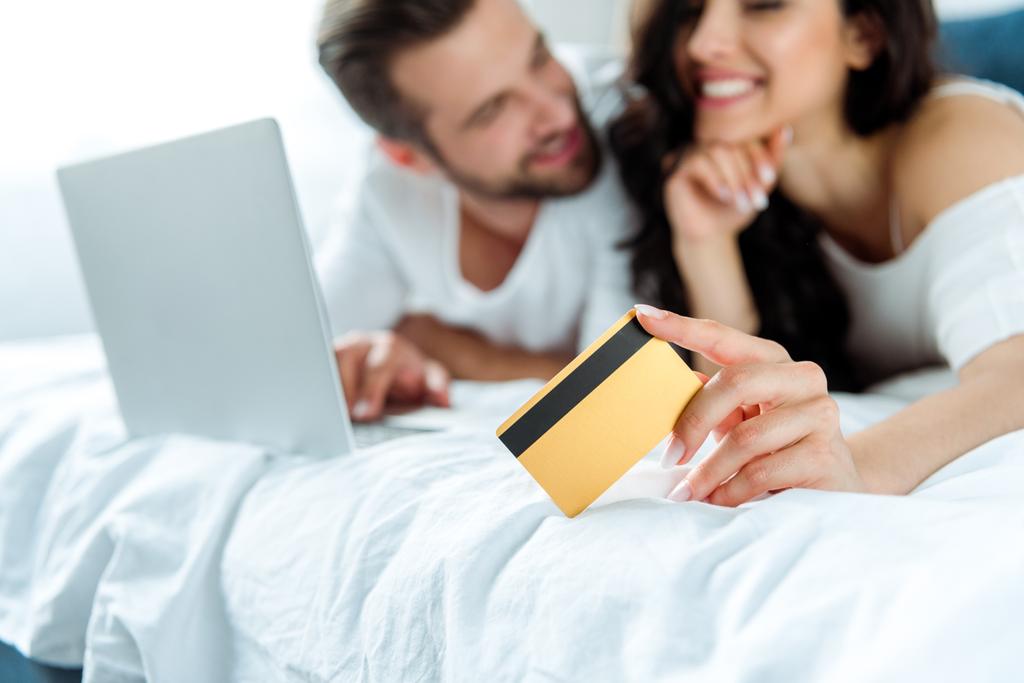 selektywne skupienie szczęśliwej kobiety posiadania karty kredytowej w pobliżu człowieka z laptopem, panoramiczny strzał - Zdjęcie, obraz